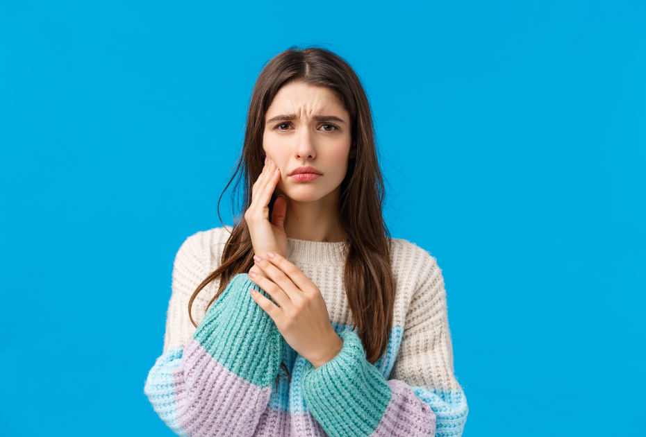 Woman holding her jaw due to tooth sensitivity, representing clear aligners for sensitive teeth UK