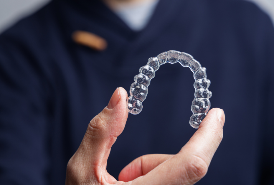 Clear dental aligner being held by a clinician, used for fast clear aligner treatment in the UK