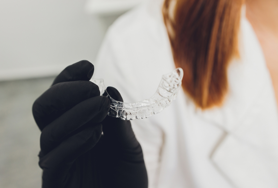 Dentist holding clear aligners in clinic – invisible aligners treatment in the UK
