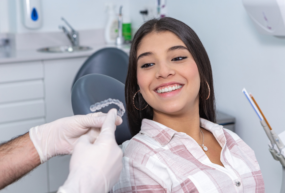 Patient discussing clear aligners treatment with dentist in clinic showing aligner tray – clear aligners results UK