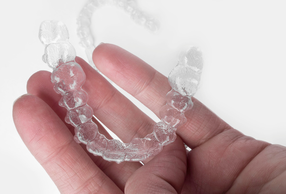 Clear aligner tray held in hand showing transparent dental aligners used for teeth straightening.