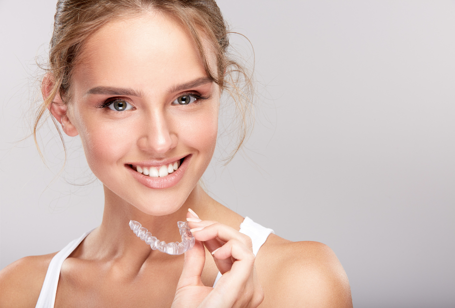Smiling woman holding a clear dental aligner, promoting invisible teeth straightening with Smileie UK.